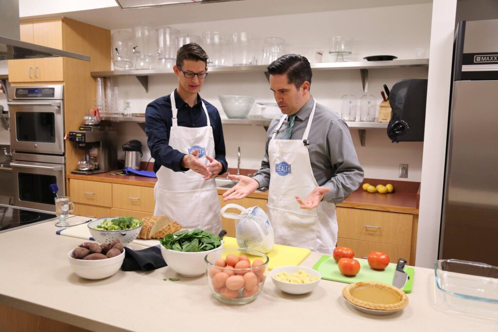 Two men in a demonstration kitchen starting to prepare a healthy dish