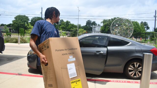 Houston Health Department worker loads a free AC unit into a car