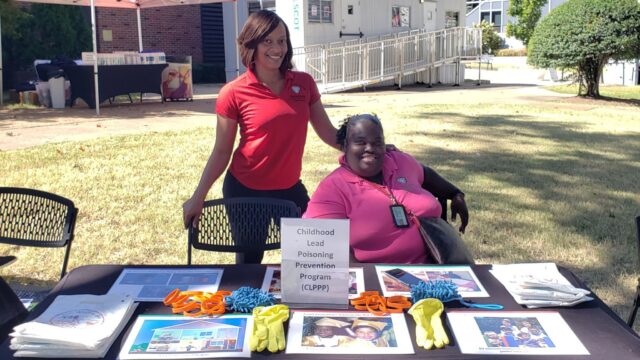 Two Shelby County Health Department professionals at a table providing information to families about how to prevent lead poisoning in children.