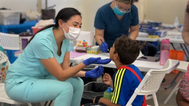 Dental clinician helps a young boy